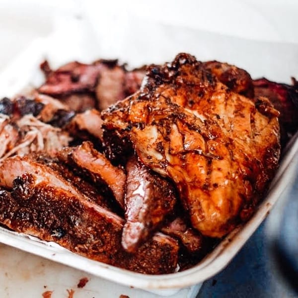 Close-up of Rack City Ribz's BBQ chicken, ribs, and pulled pork in a white tray.