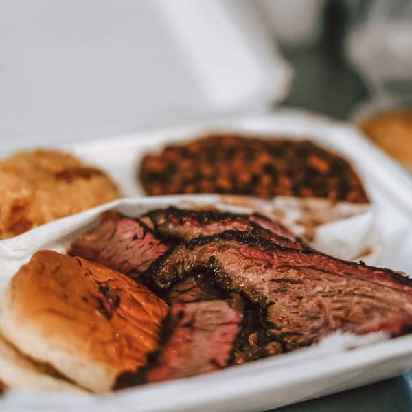 Rack City Ribz BBQ brisket, baked beans, and cornbread in a white takeout container.