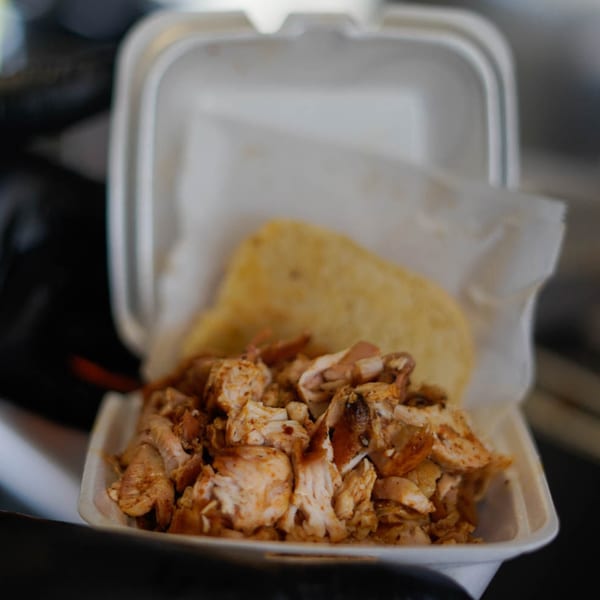 Chopped BBQ chicken and a tortilla in a white takeout container from Rack City Ribz.