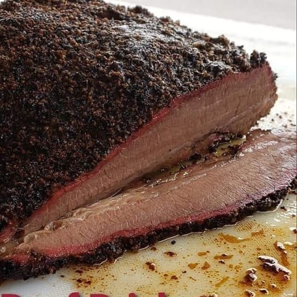 Close-up of a sliced Rack City Ribz BBQ brisket with a dark, peppery crust and a pink smoke ring.
